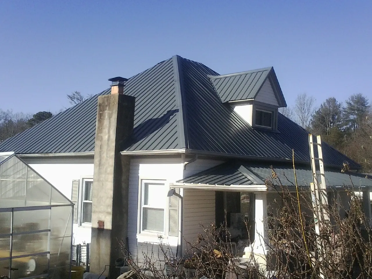 Dark blue standing seam metal roof on a white farmhouse with dormer — Slate & Tile Roof Repair by Roofing Brothers in Everetts
