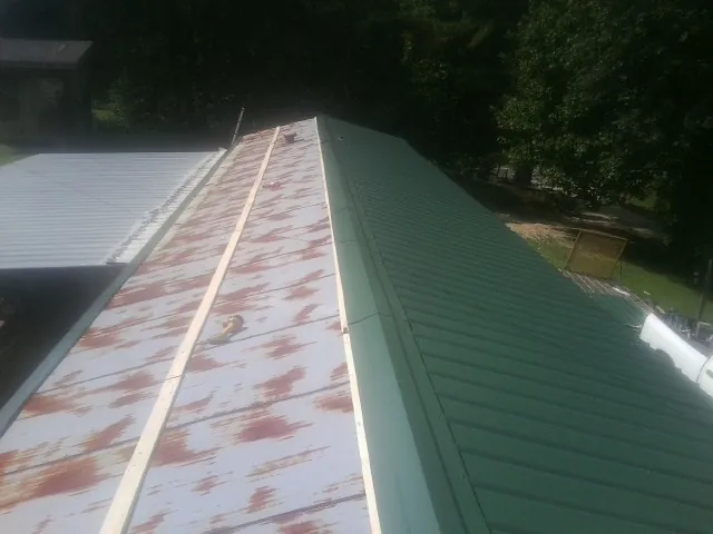 Old rusted panels beside newly installed green metal roofing — Wind Damage Roof Repair by Roofing Brothers in Everetts