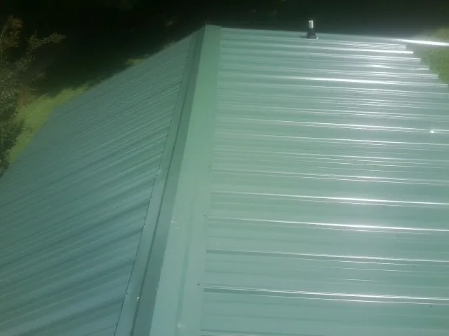 New green metal panels meeting at the ridge of a roof — Flat Roof Repair work by our crew in Everetts