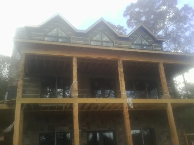 Dormers and porch framing on a large log home under construction — Roof Coating work by our crew in Everetts