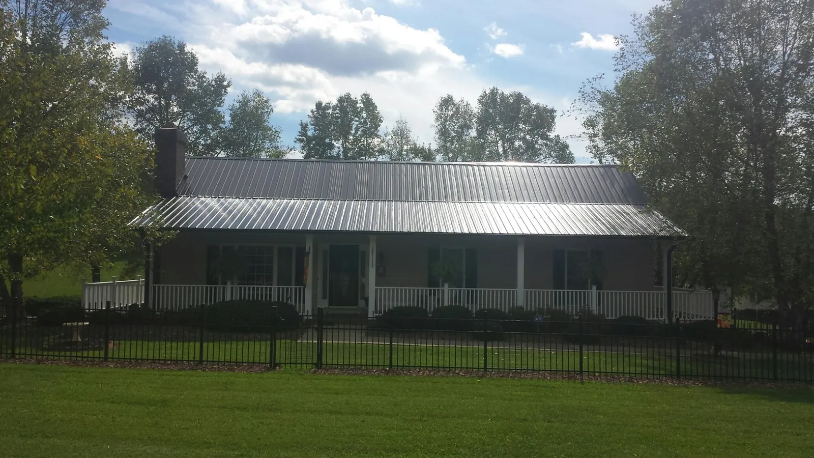 Gray metal roof on a brick ranch with a full width front porch — Gutter Guard Installation work by our crew in Everetts