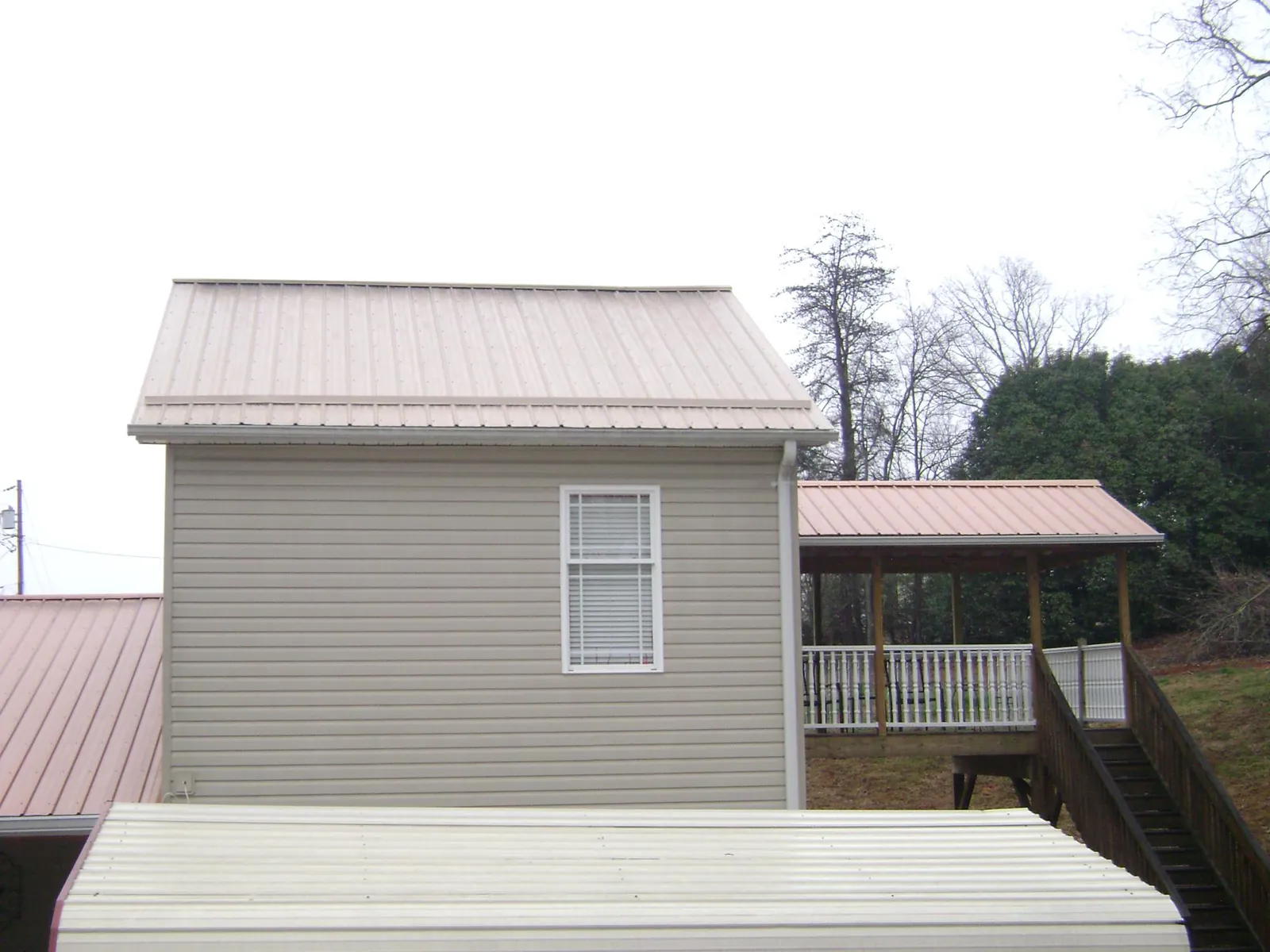 Tan metal roofs on a two story addition and attached porch, from a Roof Replacement job in Everetts